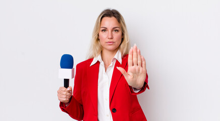 blonde pretty woman looking serious showing open palm making stop gesture. preporter and microphone concept