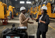 © AnnaStills - African journalist holding microphone and interviewing engineer in warehouse with new equipment