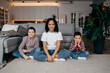 © Ankor_stock. - Happy african american family sitting on floor and looking at camera