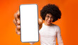 Happy black guy demonstrating smartphone with big blank white screen, showing space for your ad, app or website design