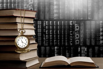 Wall Mural - old clock on a chain with stack books on library background. retro clock as a symbol of time a books