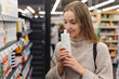 Shopping cosmetics - woman smelling bottle of shampoo in store