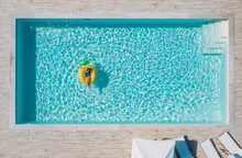Sexy Young Female In Swimsuit Bikini, In A Straw Hat And Sunglasses Floating On Blue Swimming Pool Waves On Giant Inflatable Yellow Pineapple Tube. Chill Out Summer Vacation In Luxury Resorts Concept.