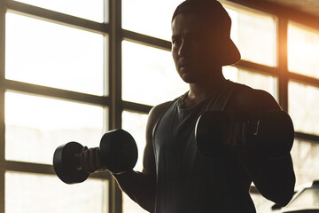 Poster - Silhouette picture of a man performing exercises with dumbbells in the gym. Strength training