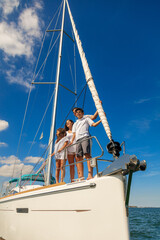 Wall Mural - Latin American family standing on bow of yacht