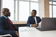 © xartproduction - Two dark-skinned partners of an African American businessman in a meeting work on a laptop in the office. Affordable private courses and distance learning. New opportunities online