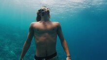 Man Swims In The Sea. Confident Freediver Stays Underwater In Maldives And Looks Around