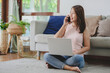 © interstid - Beautiful Asian woman talking on smartphone mobile while working with laptop notebook at home