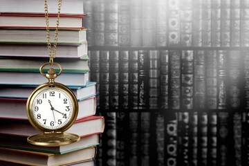 Wall Mural - old clock on a chain with stack books on library background. retro clock as a symbol of time a books