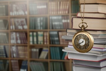 Wall Mural - old clock on a chain with stack books on library background. retro clock as a symbol of time a books