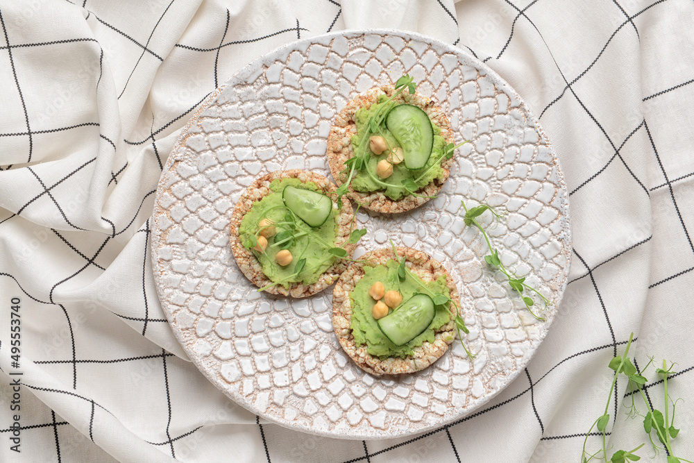 Plate with crispbreads and tasty pea hummus on table