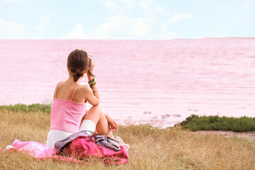 Sticker - Young tourist with backpack sitting near pink lake