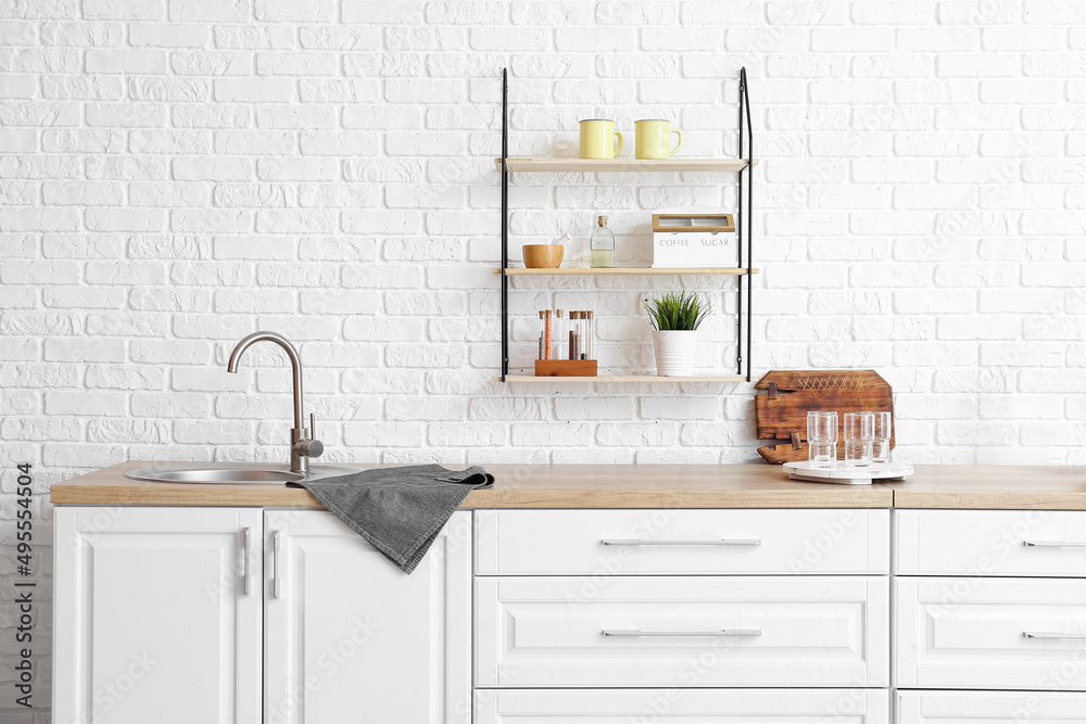 Interior of modern kitchen with white counters and empty glasses