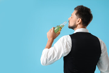 Wall Mural - Handsome bartender drinking beer on blue background