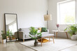 © Pixel-Shot - Interior of light living room with comfortable sofa, houseplants and mirror near light wall