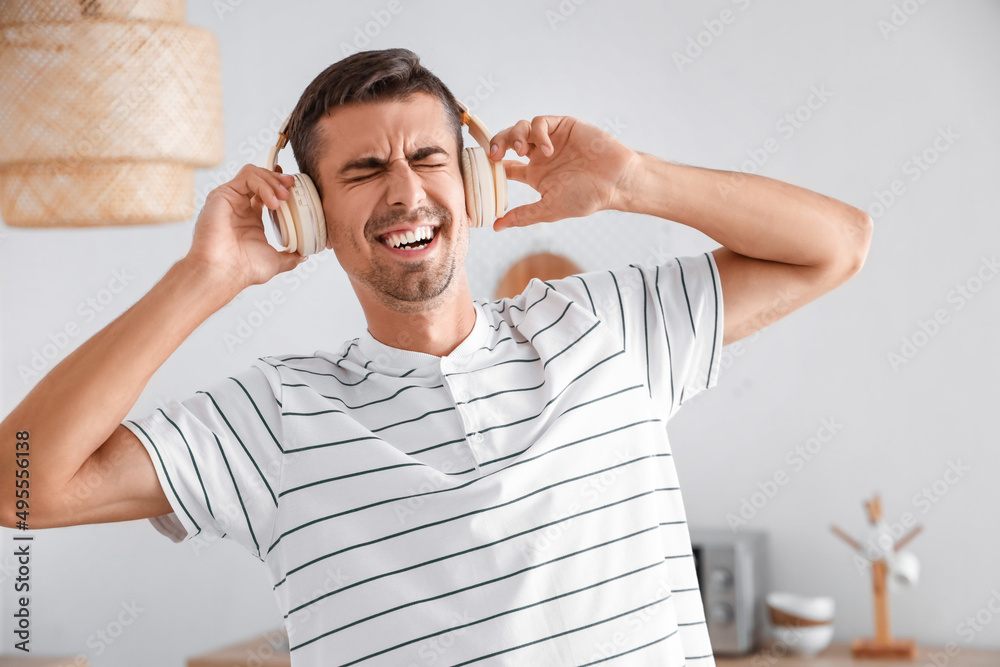 Dancing young man with headphones in kitchen, closeup