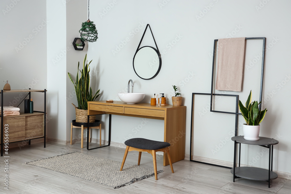 Interior of light bathroom with wooden table, sink and mirror