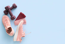 Elastic bands, dumbbells and shoes on color background