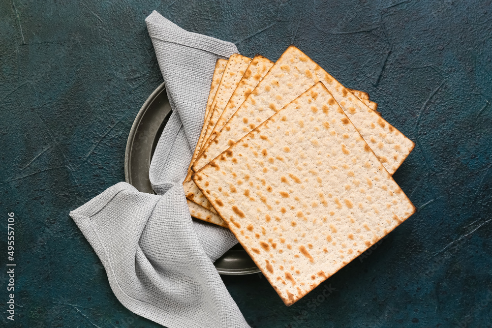 Plate with Jewish flatbread matza for Passover and napkin on dark background