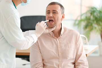 Poster - Doctor examining man with sore throat in clinic