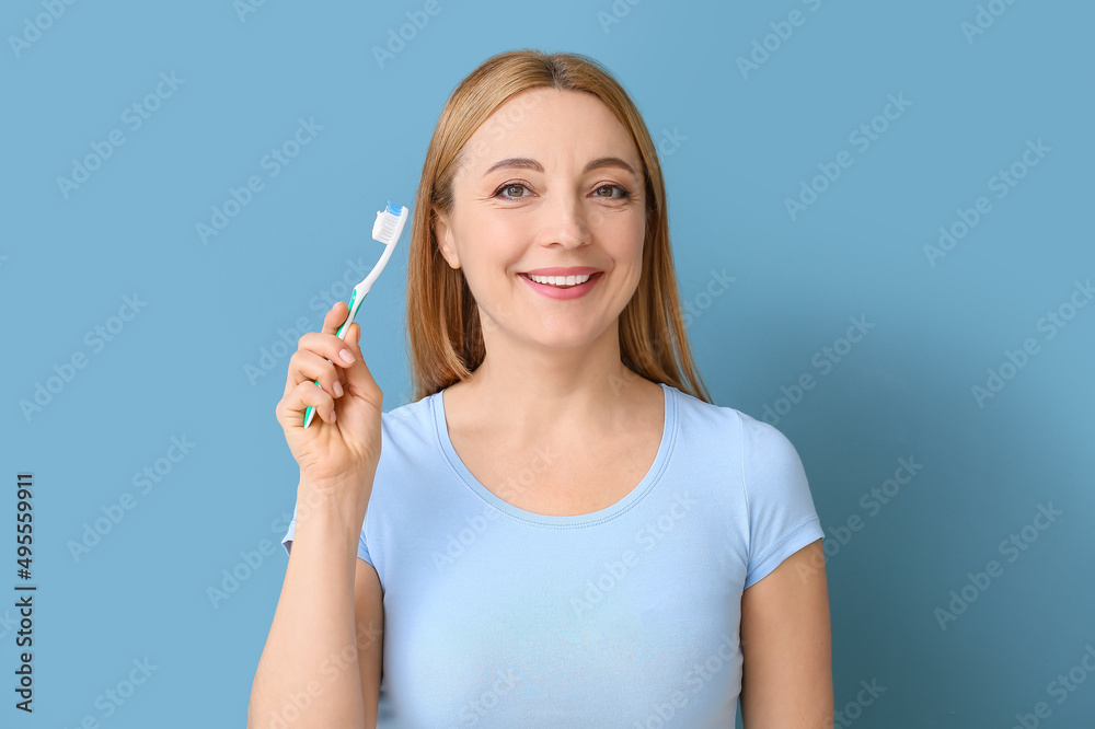 Beautiful mature woman with tooth brush on blue background