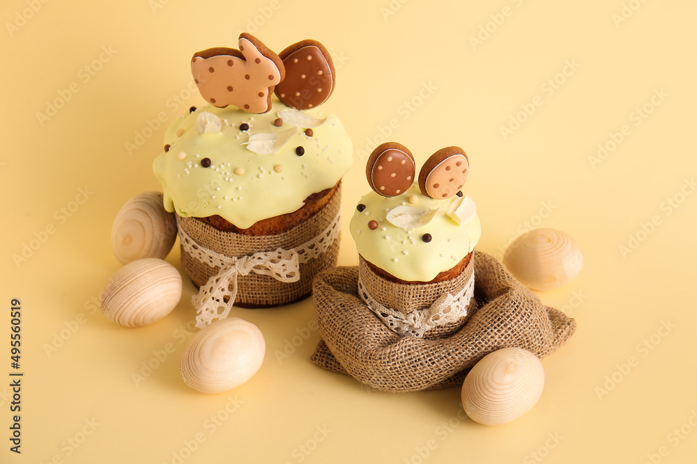 Delicious Easter cakes decorated with cookies and wooden eggs on beige background