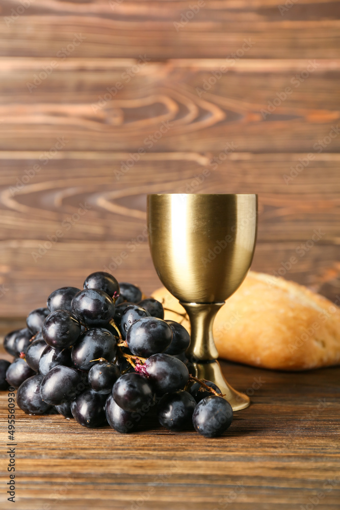 Cup of wine with grapes and bread on wooden background