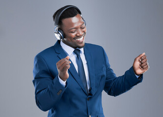 Poster - Dont forget to take a few moments for yourself. Cropped shot of a handsome young businessman using his headphones to listen to music in studio against a grey background.