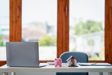 Real estate concept. Agent or banker desk with piggy bank and house model at office.