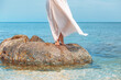 close up of woman legs standing on the stone in the sea