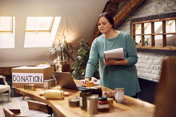 Wall Mural - Young woman uses laptop while working as volunteer at charitable donation center.