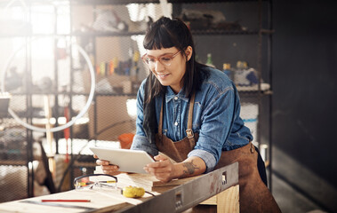 Poster - She was born to design. Cropped shot of an attractive young woman working on her tablet while standing in her creative workshop.