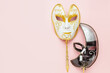 Two Venetian carnival masks are white and black on pink background. Mardi Gras or masquerade concept