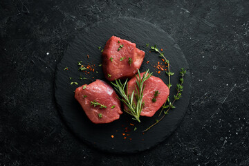 Wall Mural - Meat. Raw pork tenderloin with spices on a black stone background. Top view. Rustic style.