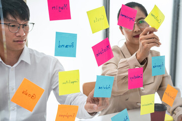 Poster - Two business people holding keyword in notes on a glass wall to brainstorm about new business project