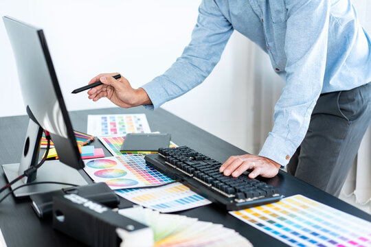Young creative graphic designer working on color selection and drawing on graphics tablet at workplace, Color swatch samples chart for selection coloring