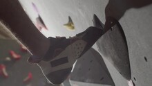 Closeup Shot Of Male Sportsman Climbing Up Bouldering Wall Indoors. Sportsman Stepping At Smooth Crimp Attached To Climbing Wall While Making His Way On Climbing Route. Sport, Climbing Concept