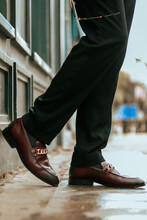 Vertical Shot Of The Lower Body Of A Man Wearing Brown Loafers With Golden Chain Buckles