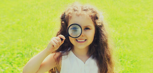 Portrait of smiling child looking through a magnifying glass in a summer day