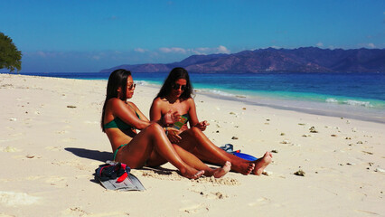 Sticker - Women  in bikinis sunbathe at the tropical Gili Meno beach, Lombok, Indonesia.