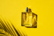 Transparent bottle of perfume with label on a yellow background. Fragrance presentation with daylight. Trending concept in natural materials with beautiful shadow. Women's essence.