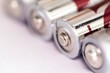 A close up portrait of the plus or positive side of a couple of triple A or AAA batteries lying on an almost white surface.