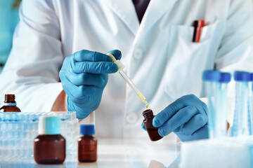 Pharmacist pipetting fluids into a bottle in the research department for the pharmaceutical industry. Scientist or researcher medical holding test tube and dropping reagent in the biochemistry lab. 