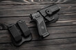 Pistol and plastic holster on a wooden back. A short-barreled weapon and a flashlight near the tactical backpack.
