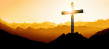 Religious Grief Landscape Background Banner Panorama - View With Black Silhouette Of Mountains Alps, Hills, Forest And Cross / Summit Cross, In The Evening During The Sunset, With Orange Colored Sky..