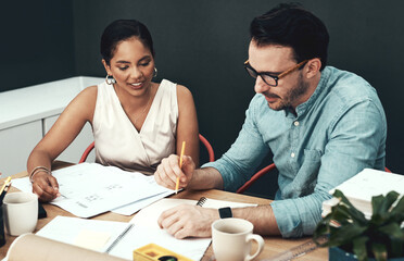 They work well together. Cropped shot of two young architects working together in a modern office.