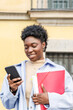 © ADDICTIVE STOCK - Positive black woman with folder on mobile phone