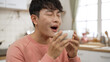 © PR Image Factory - closeup shoulder shot of smiling asian male enjoying a bowl of hot soup at lunch in bright dining room. he blows on it and gives praise with satisfied expression on face