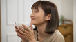 © PR Image Factory - shoulder shot portrait of asian smiling woman enjoying delicious hot soup from the bowl with satisfied expression on face at home