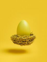 Yellow colored egg and bird nest flying on a matching monochrome yellow background. Minimal Easter holiday or food concept. Creative festive Easter greeting card with a copy space for text.